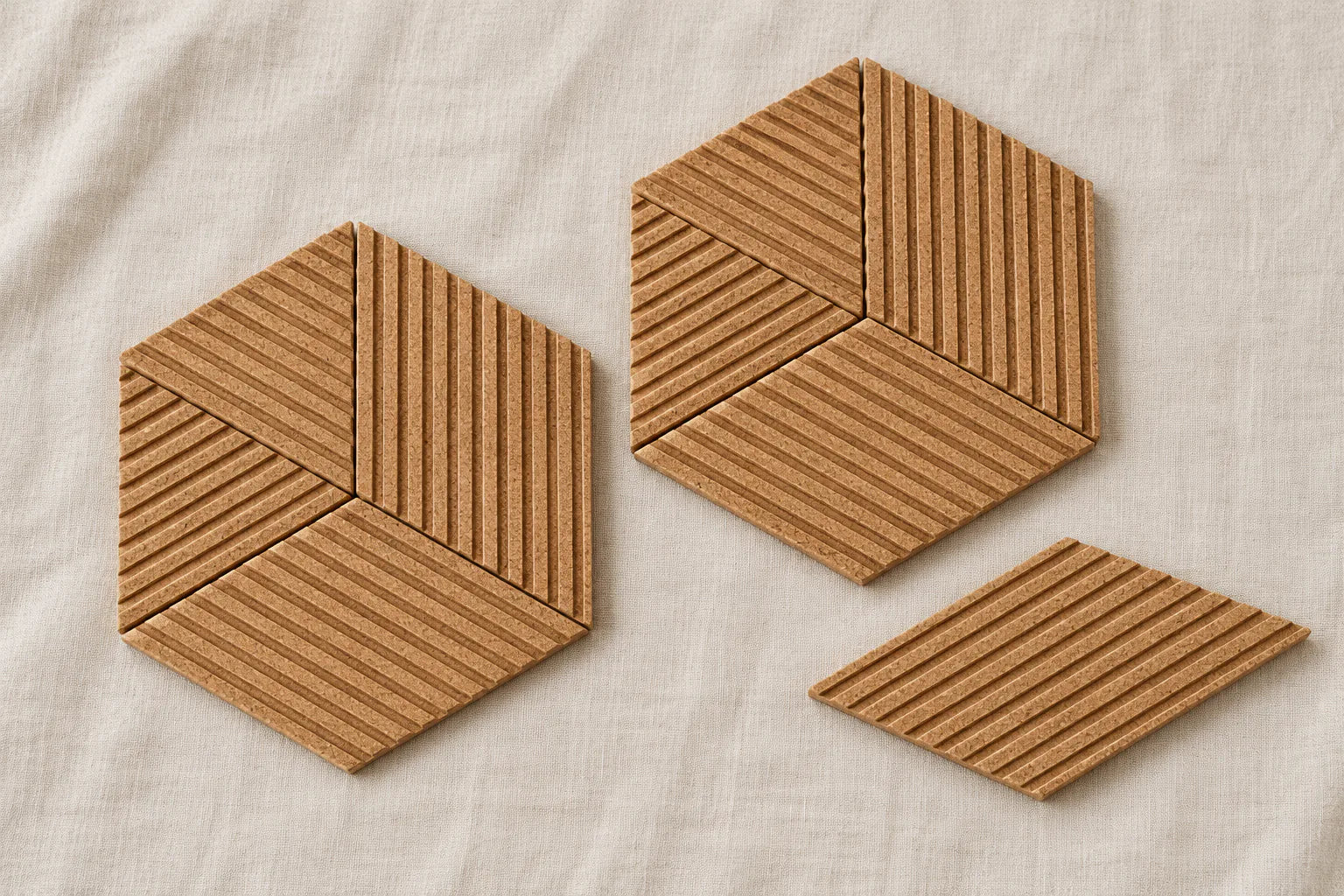 Ribbed rhombus cork tiles arranged on a work surface to plan a geometric pattern.